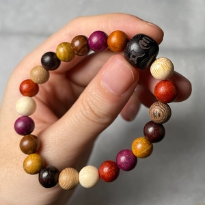 Detailed view of colorful multi-wood prayer beads held by hand showing texture and size