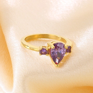 Macro view of gold stainless steel ring with pear shaped purple zircon on silk fabric