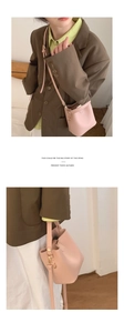 Detail view of a pink synthetic leather bucket bag with shoulder strap and drawstrings