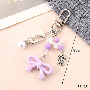 Detailed view of purple acrylic bow keychain with silver beads and handcrafted metal tag