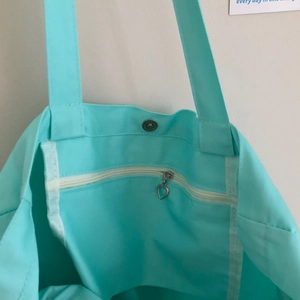 Detail der mintgrünen Canvas-Tasche mit Magnetverschluss und Herz-Reißverschlusstasche