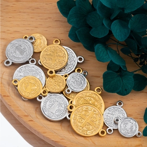 Religious Saint Benedict medal pendants in gold and silver finish on a wooden tray