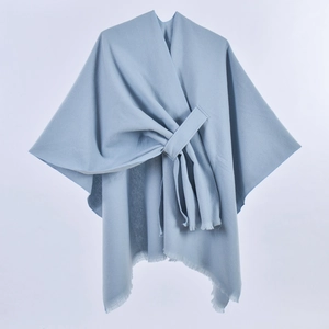 Detail of light blue shawl featuring soft fabric texture and elegant fringe tassels
