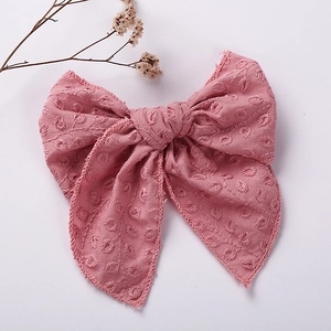Close-up of pink cotton bow hair clip featuring intricate 3D floral embroidery details