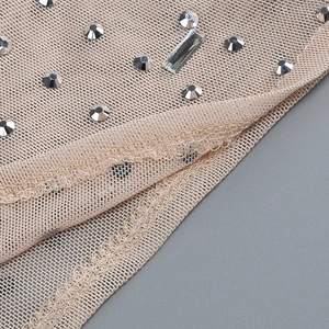 Macro shot of silver rhinestones on sheer nude mesh fabric with fine stitching details