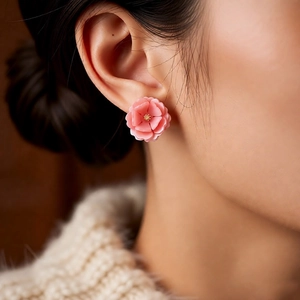 Macro detail of a 3D pink resin flower earring featuring layered petals and golden stamens