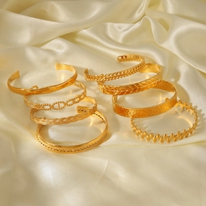 Vue détaillée de sept bracelets ouverts en acier doré 18K sur un tissu en soie