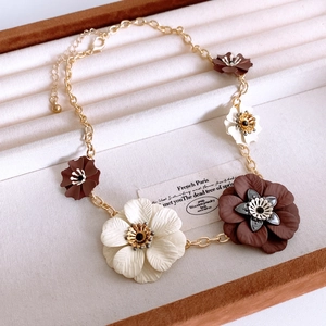 Close-up of golden floral necklace with white and brown petals in luxury gift box