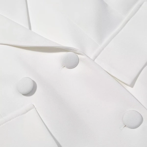 Detailed close-up of white blazer jacket featuring matching fabric-covered buttons and seam