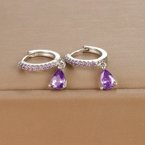 Detail of silver drop earrings with pear-cut purple zircon and pavé setting