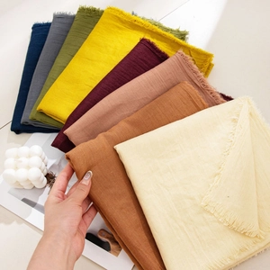 Close-up of multicolored cotton linen scarves with fringe details in various earth tones