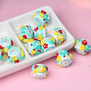 Macro detail of DIY light blue acrylic beads with dessert patterns in a ceramic dish