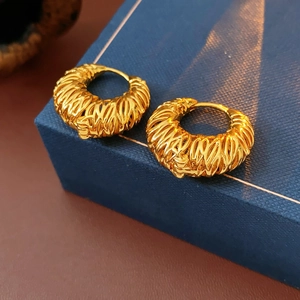 Detail of 18k gold plated hoop earrings with woven texture on a blue jewelry box