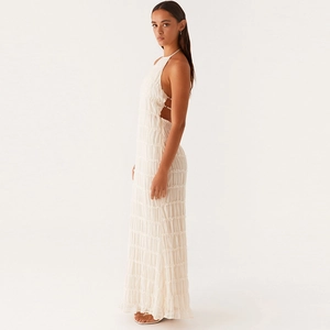 Detail of white pleated maxi dress with tiered ruffles and backless tie design