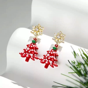 Detail view of Christmas tree earrings with golden snowflake and red tree design