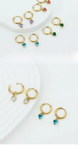 Macro detail of heart-shaped crystal charms on gold huggie earrings in multiple colors
