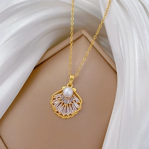 Detailed shot of a gold shell pendant with crystals and pearl on white silk fabric