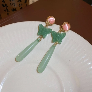 Macro shot of retro butterfly drop earrings with pink cat-eye stone and green resin charms