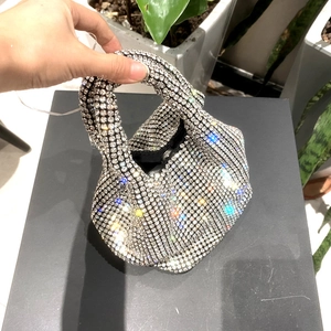 Detail of silver rhinestone evening bag featuring a trendy knotted handle and pleated design