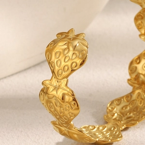 Macro detail of 18K gold plated strawberry relief texture on an open cuff bracelet