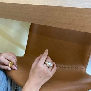 Primer plano de anillos minimalistas en metal dorado y plateado en la mano de una modelo