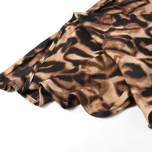 Detailed macro view of leopard print satin fabric with elegant ruffled hemline finish