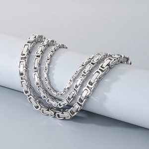 Detail of silver Byzantine chains in various thicknesses displayed on a grey pedestal