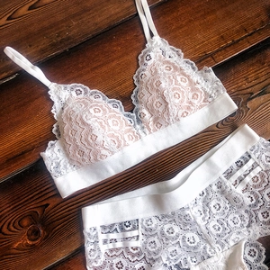 Ensemble bralette en dentelle florale blanche posé sur bois sombre avec bandes élastiques