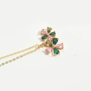 Close-up of golden double flower pendant with pink and green teardrop gemstones