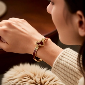 Macro shot of 18k gold plated gourd buckle bangle with red enamel details for women