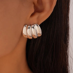 Macro view of textured geometric silver stud earrings with high-polish rippled finish