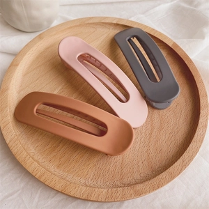 Detailed view of matte finish hair clips in pink brown and grey on a wooden plate