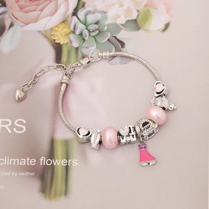 Detail of silver snake chain bracelet with pink enamel heart and crown charms