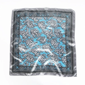 Flat lay of a satin square scarf with sky blue and silver paisley patterns
