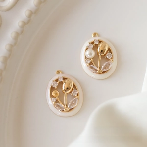 Detailed macro of gold oval tulip pendant with white oil drip finish and pearl inlay
