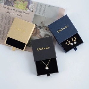 Chic drawer-style jewelry boxes in gold, black, and navy blue with pearl accessories