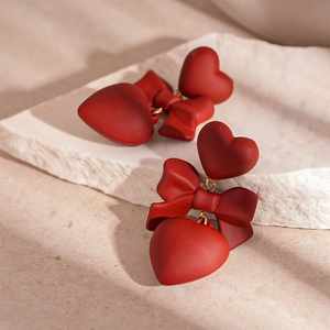 Vintage Ancora red heart drop earrings with bow accents on natural stone background