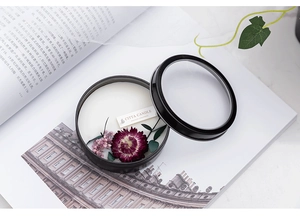 Top view of natural scented candle in black tin with dried flowers and glass lid