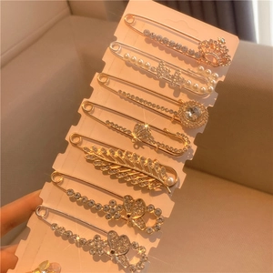 Detailed close-up of set of 7 decorative safety pin brooches with pearls and rhinestones