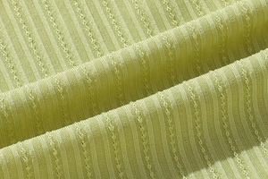 Detailed macro view of light green ribbed knit fabric with decorative breathable holes