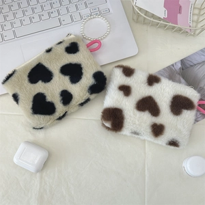 Close-up of plush heart-pattern coin bags with pearl chain on an aesthetic desktop