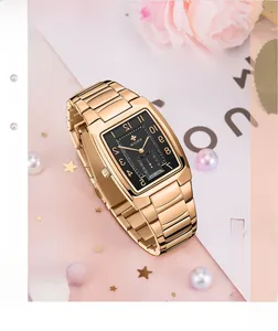 Detail einer luxuriösen goldenen Quarzuhr mit schwarzem Zifferblatt neben Perlen und Blumen
