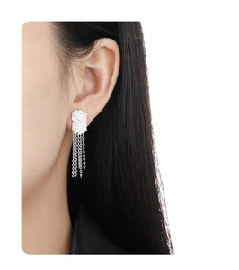 Detail showing irregular silver tassel earrings on model with modern geometric design