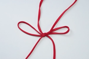 Gros plan détaillé d'une bandoulière en tissu élastique rouge nouée en un joli nœud décoratif
