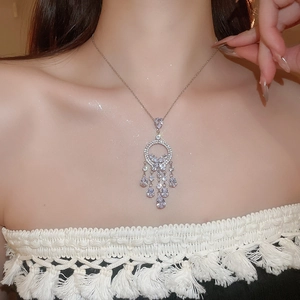 Gros plan du collier à glands argenté avec papillon et zircons en goutte sur un mannequin