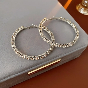Macro shot of silver circular hoop earrings with sparkling crystals on grey velvet box