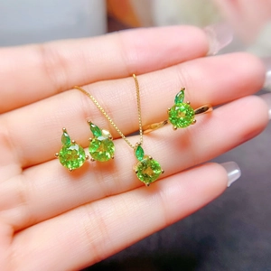 Exquisite apple-themed jewelry set with green gemstones in gold finish on hand