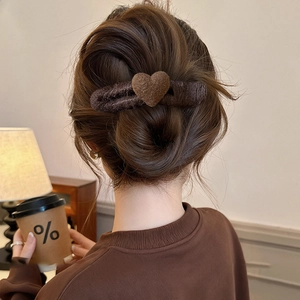 Detail of dark brown wool heart hair clip worn on back of head in cozy lifestyle setting