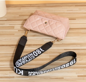 Detailed close-up of pink quilted crossbody bag with stylish patterned wide shoulder strap