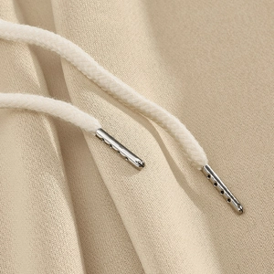 Detail of khaki jogger pants showing cotton fabric texture and metallic drawstring tips